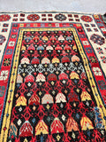Red, blue, and ivory tribal runner rug with geometric rosettes and flowering motifs.
