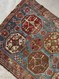 Time worn Caucasian rug showing mellowed natural dyes and low pile wool texture.