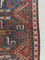 Tribal Caucasian rug featuring ram’s horn and eight-pointed star designs.