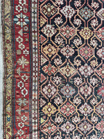 Antique Caucasian rug showing bold floral chain on red ground.