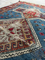 Handwoven Caucasian rug featuring ram’s horn motif for strength.