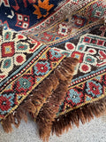 Close up of handwoven 19th century Caucasian rug with rows of symbolic tribal motifs and natural dyes.