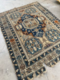 Late 19th century Caucasian tribal rug with deep blue field and orange outlined medallion.