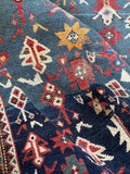 Antique Caucasian rug with striking blue ground and playful tribal drawing woven by village weavers.