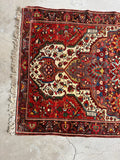Antique rug with detailed floral medallion and rich contrast.