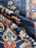 Blue and peach antique runner highlighting the warm floral details against the dark navy background.