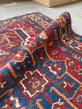 Hand knotted antique Heriz rug with low pile and scattered age wear throughout.