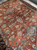 Warm-toned Heriz rug with angular vines and stylized palmettes
