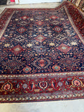 Full view of large antique 1920s Persian Heriz rug with tribal design.
