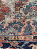 Detail of dusty coral tones and denim blues in antique Heriz rug.