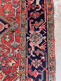 Antique Heriz rug turtle motif border close up framing a dark midnight blue and dark red perimeter.