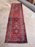 Vintage Gharajeh tribal runner from the 1920s laid out to showcase its bold geometric patterns and long hallway scale.