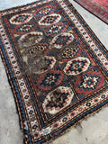 Antique Caucasian Kazak rug with geometric tribal design and timeworn character.