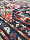 Blue and red Kazak runner rug with folk art geometric medallion design.
