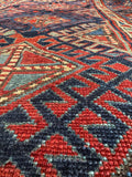 Close up of handwoven Kazak rug detail showing vegetable dyed wool and tribal motifs.