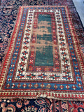 Antique Caucasian Kazak rug featuring an open green field and tribal borders, size 4x7.