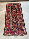 Full view of antique Kazak runner with tribal symbolism in vibrant colors.