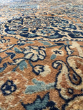 Closeup view of antique Persian Kerman rug in warm camel and blue tones.