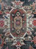 Close up of 1920s Kurdish area rug showing a bold central medallion framed by floral chain edge guards.