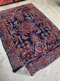 Antique floral Persian rug with raspberry, coral, celadon, and ivory details.