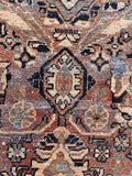 Distressed Persian area rug close up shot highlighting course weave texture and low-pile wear.