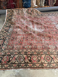 Antique Mahal village rug with brick red field and floral motifs.