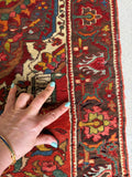 Vintage Persian rug detail highlighting intricate curvilinear floral border work and also showing some areas of wool loss.
