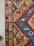 Persian geometric medallion rug displaying intricate border bands and vibrant contrast colors.