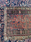 Distressed antique Persian scatter rug with handmade tribal motifs and dense wool construction.