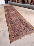Timeworn navy blue runner rug from early 1900s Persia laid out to display its full vintage length and character.