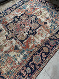 Antique Persian Heriz rug showing scattered wear over beautiful woven art.