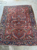 Antique Persian Heriz rug. Hand knotted 1920s wool area rug with a warm terracotta field, bold geometric design, and midnight blue border.