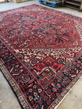 Antique Persian Heriz rug. Large hand knotted wool area rug with a brick red field, bold geometric medallion, and richly detailed floral borders.