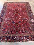 Hand knotted wool rug with red and blue tribal pattern.