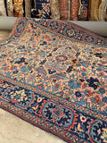 Salmon Persian Heriz rug close up featuring angular geometric florals, serrated leaves, and branching vines.
