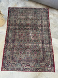19th century Persian Lavar rug with dark navy scrolling ribbon border design.