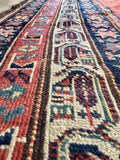 Antique 1900s Persian rug close-up showcasing detailed ivory, navy, and terracotta floral border art.