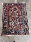 1930s Northwest Persian rug showcasing a full view of the geometric tribal pattern on concrete flooring.