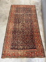 Full view of 1920s Persian rug with tree of life border on rust red ground.