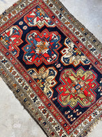 Small Persian rug featuring eight-pointed star motifs.