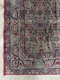 Worn antique Persian Kerman rug featuring a softened patina and low distressed pile.
