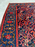 Detailed shot of vibrant blue border with floral art framing antique Persian paisley field.