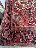 Antique Heriz rug with ornate border work framing a bold central medallion.