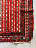 Antique Persian small area rug featuring traditional geometric striping, star symbols, and some corner wear.