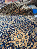 Close up of center design in navy antique Persian rug with soft plush wool pile.