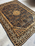 Angled photo showing navy Herati pattern antique Persian rug and detailed border.