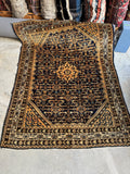 Antique Persian rug with navy blue Herati field and warm golden accents.