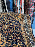 Antique Persian rug corner with Herati pattern and geometric floral detailing.