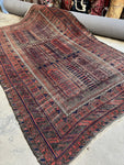 Antique Persian Baluch rug full view showing aged wool and tribal motifs.