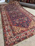 Antique 1920s Persian rug with navy blue ground and floral motifs.